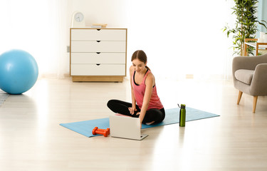 Sporty young woman with laptop at home