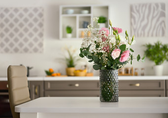 Vase with beautiful flowers on table in kitchen
