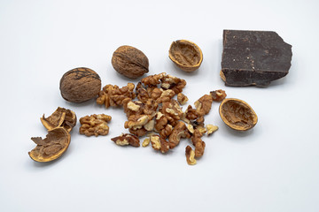 Freshly harvested organic wallnuts and black chocolate, white background.