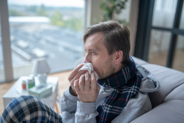 Bearded man holding napkin while having stuffy nose