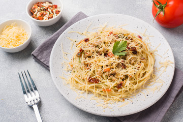 Spaghetti pasta Bolognese with vegetable sauce and cheese. Portion on a plate. Light concrete background.