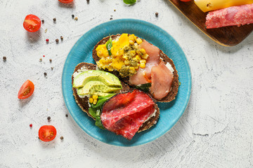 Plate with tasty sandwiches on light background