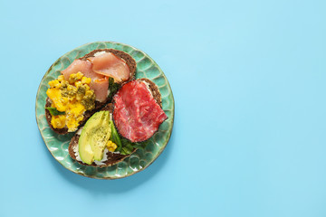 Plate with tasty sandwiches on color background