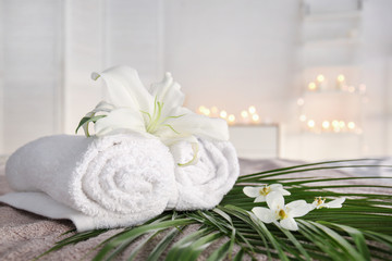 Obraz na płótnie Canvas Rolled towels with fresh flowers and tropical leaves in spa salon