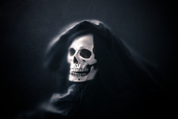 Fototapeta na wymiar Grim reaper in the dark behind a dusty scratched glass.
