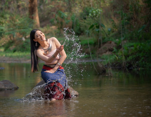 Beautiful woman wearing a northern style dress Standing in the stream.