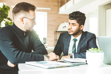 A team of young businessmen working and communicating together in an office. Corporate businessteam and manager in a meeting.