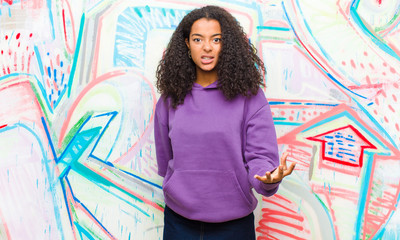 young pretty african american woman looking angry, annoyed and frustrated screaming wtf or...