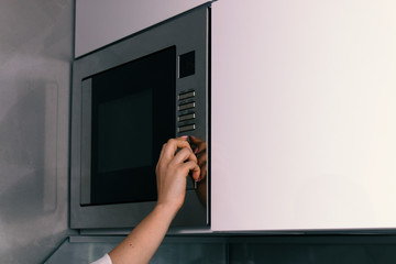 girl warms up food in the microwave