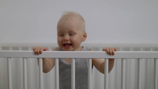 cute smiling baby boy playing in cot