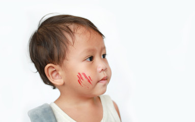 Portrait of little Asian baby boy with face make up sticker lesion on face in Halloween costume looking out over white background.