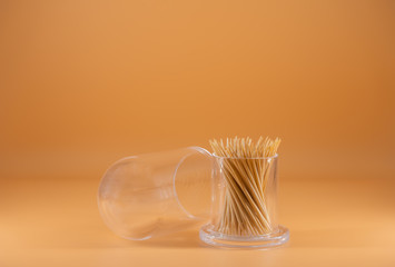 A toothpick in a plastic bottle with the lid of the bottle placed near With an orange background and isolated