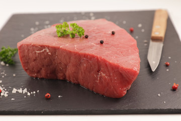 raw piece of beef on blackboard with spices