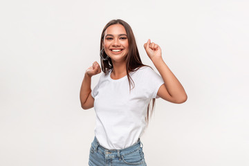 Obraz na płótnie Canvas Beautiful african-american teenager in a white t-shirt and blue jeans dancing isolated over white background.