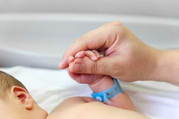 The baby clings to his mother's finger