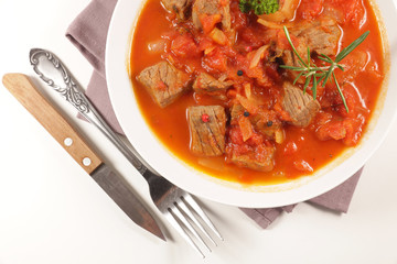 beef stew with tomato sauce and herbs on white background