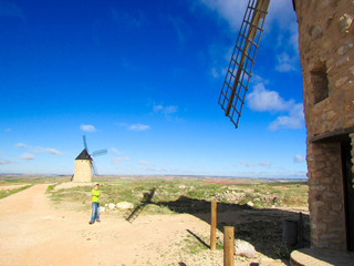 Young tourist boy stay under famous castilla-la mancha windmills