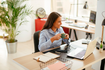 Young businesswoman drinking coffee in her office	