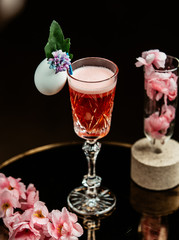 light red drink in crystal glass with stand garnished with flowers