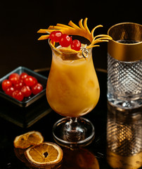 orange juice with ice cubes, garnished with orange skin, candied cherries