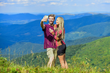 Naklejka na ściany i meble Couple taking photo. Summer vacation concept. Young adventurers. Travel together with darling. Couple in love hiking mountains. Lets take photo. Capturing beauty. Man and woman posing mobile photo