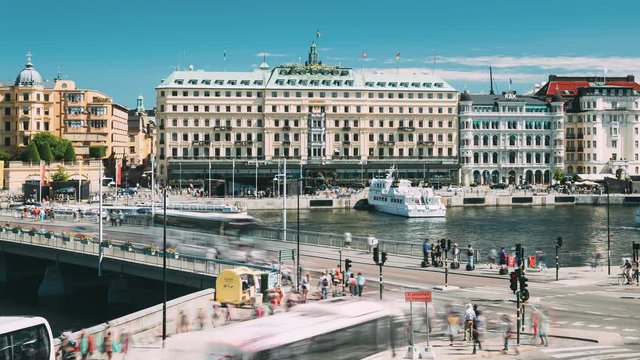 Stockholm, Sweden - June 28, 2019: Traffic With Cars And Buses. Grand Hotel Located On The Peninsula Blasieholmen. Touristic Pleasure Boats Floating Near Famous Grand Hotel In Sunny Summer Day
