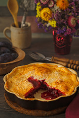 Home-baked autumn red fruit pie, in a brown ceramic pie plate, ready to serve.
