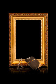 Remembrance of loss. Personal keepsake item. Empty golden wooden frame with a and steel dog tag on black background.
