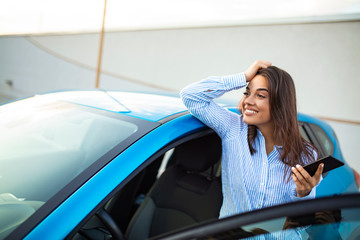 Road trip, technology and communication concept - happy young woman calling on smartphone near car. Business Woman Uses Smartphone While Leaning on Her Car