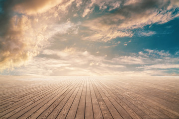 Empty wooden floor against cloudy sky with sunset.