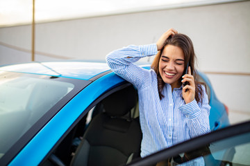 Successful woman standing by her car texting on mobile phone. Pretty woman with smartphone. Beautiful elegant woman texting outdoors. Businesswoman talking on the phone