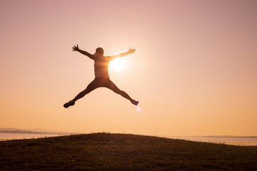 silhouette of Jumping Man on the peaks and backgrounds of sunrise or sunset,men trail running, the sky at sunrise running in the mountains, lifestyle © CStock