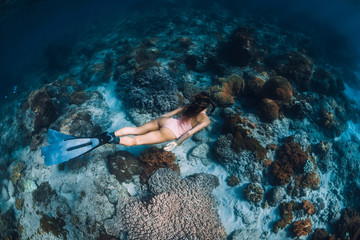 Freediver woman with fins dive to coral bottom. Freediving in a tropical ocean