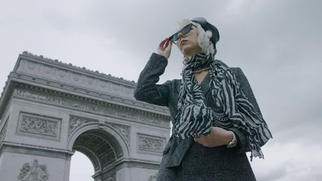 Outdoor autumn fashion portrait of elegant, luxury woman wearing trendy black boucle blazer, sunglasses, leather beret, zebra print silk scarf, posing near Triumphal Arch in Paris