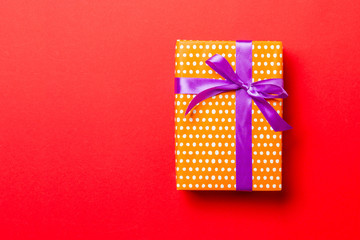wrapped Christmas or other holiday handmade present in paper with purple ribbon on red background....