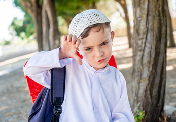 Arabic muslim boy with his backpack on his back going to school