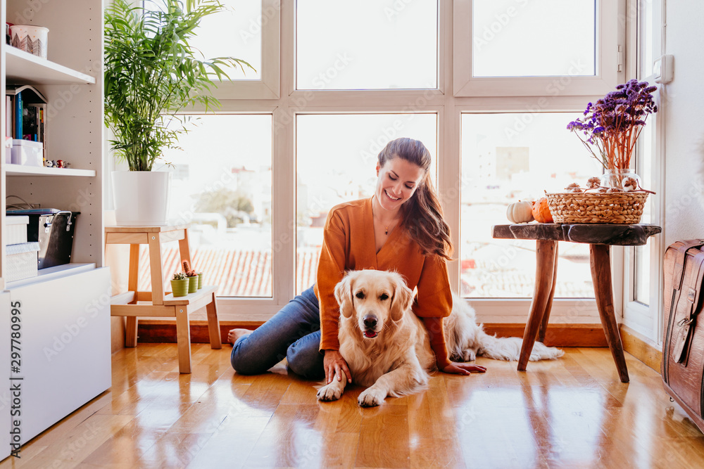 Wall mural beautiful woman hugging her adorable golden retriever dog at home. love for animals concept. lifesty