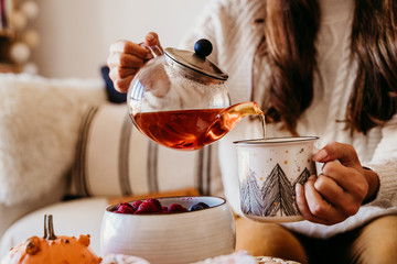 woman having a cup of tea at home during breakfast. Cute golden retriever dog besides. Healthy breakfast with fruits and sweets. lifestyle indoors - 297781100