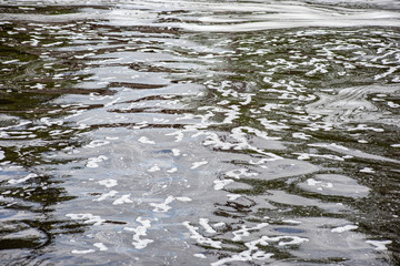 Muddy water surface with white stains, soft focus