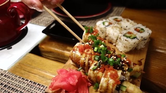 Man eating delicious sushi with chopsticks, dipping sushi in soy sauce at the restaurant Tanuki.