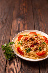 Pasta bolognese with tomato sauce and minced meat, grated parmesan cheese and fresh parsley - homemade healthy italian pasta on rustic wooden background.