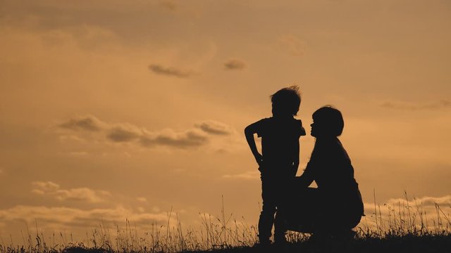 happy family mother and son outdoors silhouette concept slow motion video. mom girl hugs takes care lifestyle of her son little boy silhouette at sunset teamwork. happy family sweet childhood