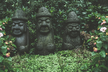 Fototapeta premium sculptures of Dol Hareubangs on rainy day with green plants