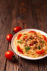 Pasta bolognese with tomato sauce and minced meat, grated parmesan cheese and fresh parsley - homemade healthy italian pasta on rustic wooden background.