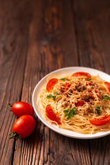 Pasta bolognese with tomato sauce and minced meat, grated parmesan cheese and fresh parsley - homemade healthy italian pasta on rustic wooden background.
