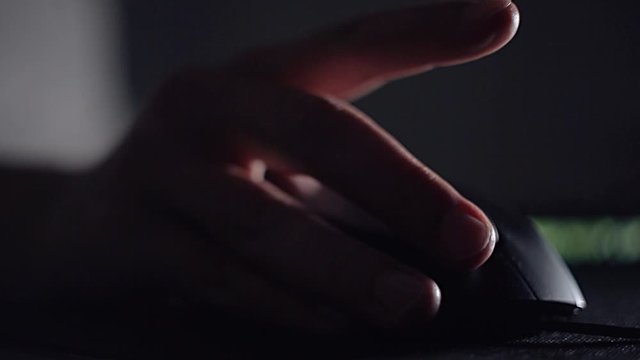 The user works at the computer using a computer mouse, modern computer technology. Programming, surfing the Internet and playing computer games in a dark room.