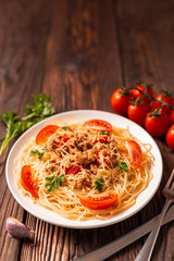 Pasta bolognese with tomato sauce and minced meat, grated parmesan cheese and fresh parsley - homemade healthy italian pasta on rustic wooden background.