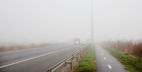 Fototapeta premium The asphalt road outside the city and thick fog above it in the morning