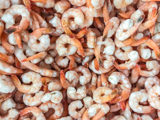 Close-up of a pile of frozen orange shrimps. Peeled shrimp, leaving only tails. Natural seafood background