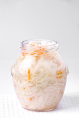 Fermented cabbage with carrots in a jar on a white background. Homemade food. Copy space